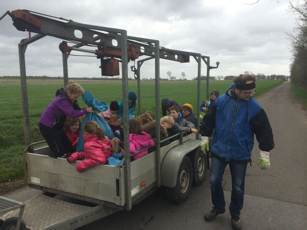 Kinder mit Müllsäcken auf einem Anhänger