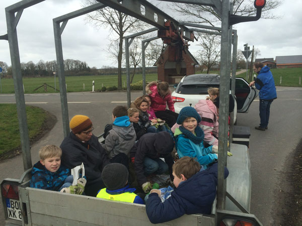 Kinder mit Müllsäcken auf einem Anhänger